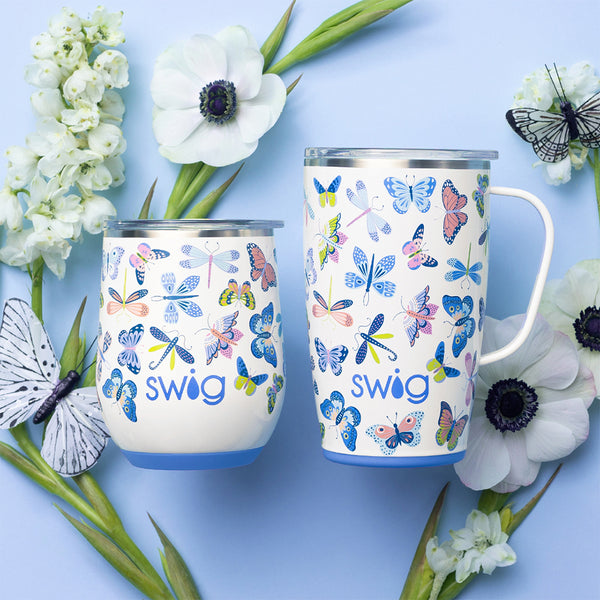 Swig Life Butterfly Bliss Insulated 18oz Travel Mug and 12oz Stemless Wine Cup surrounded by flowers and butterflies