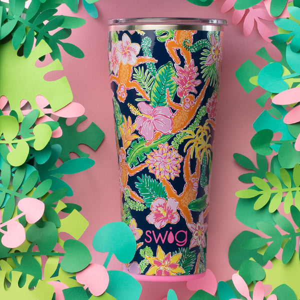 Swig Life 32oz Jungle Gym Insulated Tumbler on a pink background surrounded by tropical plants