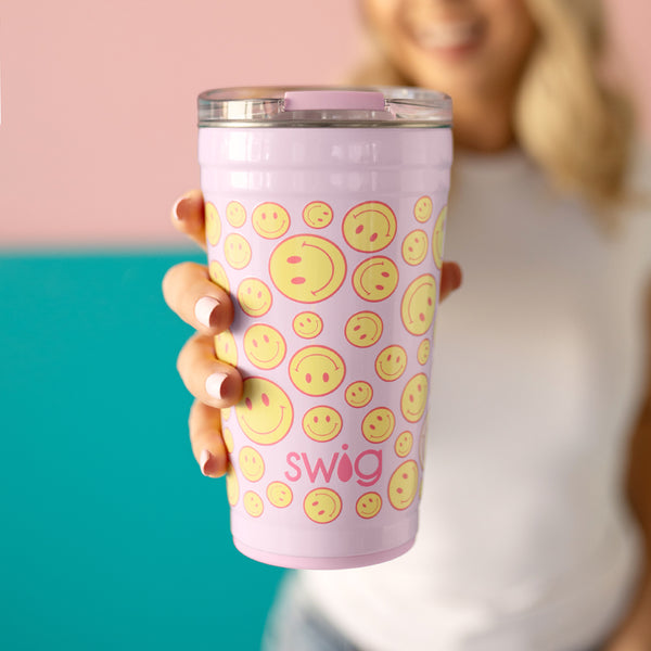 Swig Life 24oz Oh Happy Day Insulated Party Cup being held by a women on a pink background