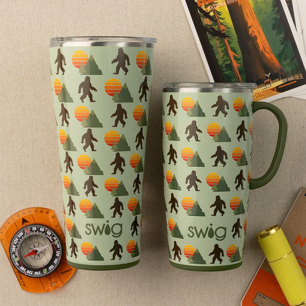 Swig Life Wild Thing Insulated 32oz Tumbler and 22oz Travel Mug on a brown background with forest navigation tools